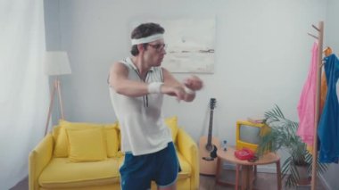 Enerjik sporcu oturma odasında ısınıyor, retro spor konsepti.