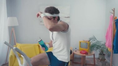 Egzersiz bisikleti ve oturma odasında içme suyu eğitimi almış yorgun bir sporcu.