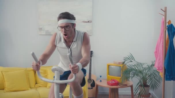 Sportler Mit Brille Trainiert Auf Heimtrainer Wohnzimmer — Stockvideo