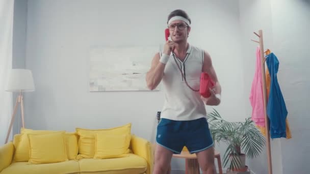 집에서 엉덩이를 흔들면서 전화로 말하는 스포츠맨 — 비디오