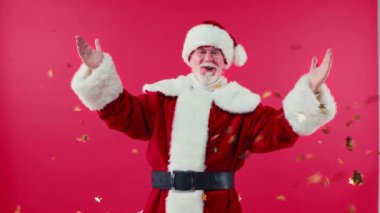 Parlayan yıldız şeklindeki konfeti altında kırmızı renkte izole edilmiş heyecanlı Noel Baba.