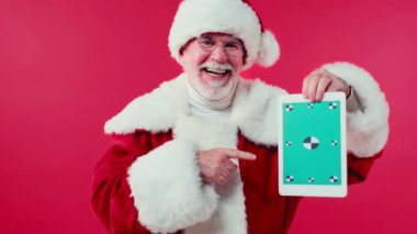 Gülümseyen Noel Baba dijital tableti işaret ediyor kırmızı üzerinde izole