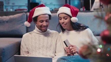 Noel Baba şapkalı mutlu Afro-Amerikan çift online alışveriş yapıyor. 