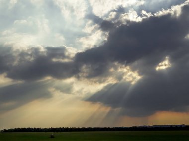 Manzara ve uzak ormanın bulutların arasında güneş parlıyor