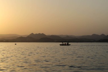 Tekne ile Hint günbatımı önünde dağlar