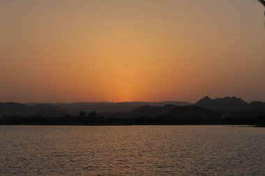 Tekne ile Hint günbatımı önünde dağlar