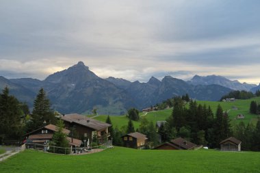 İsviçre, fırtına önde geliyor, geleneksel evleri ve yeşil çim ile pitoresk sahne güzel bir akşam
