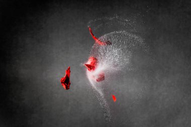 Kırmızı balon parçaları ve su damlalarının yüksek hızda yakalanması 