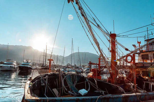 Details of the ship. Fishing nets, knots and ropes in the rays of the sunrise. Reflection in water.