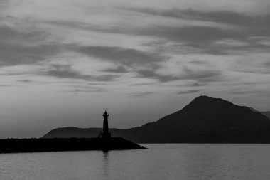 Deniz feneri günbatımı. Dağlar fonunda. Siyah beyaz resim