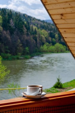 Dağlar ve nehir manzaralı, dikey boyda bir fincan kahve.