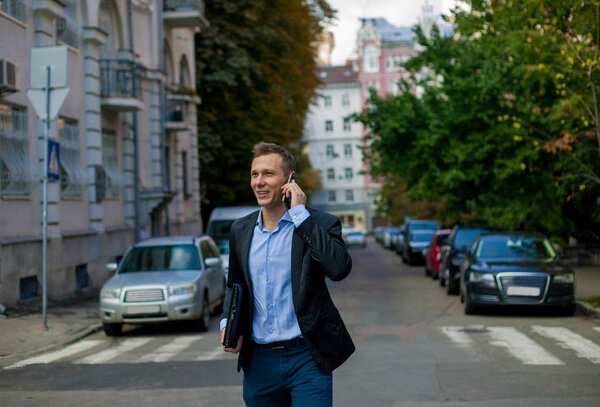 businessman in suit with laptop in the city talking on the phone