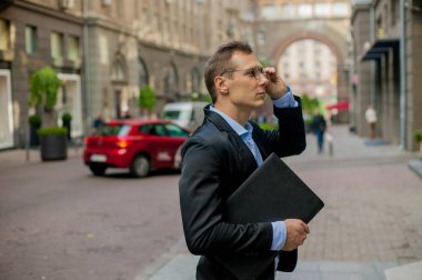 gözlük ve şehir içinde laptop ile bir takım elbise içinde başarılı iş adamı