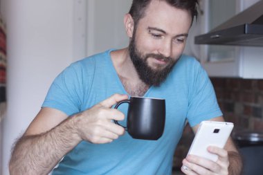 yakışıklı bir adam kahve içer ve telefona benziyor