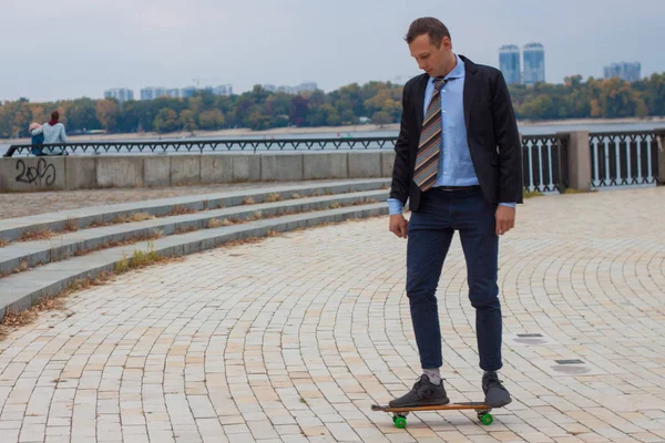 businessman in business suit in the city with skateboard