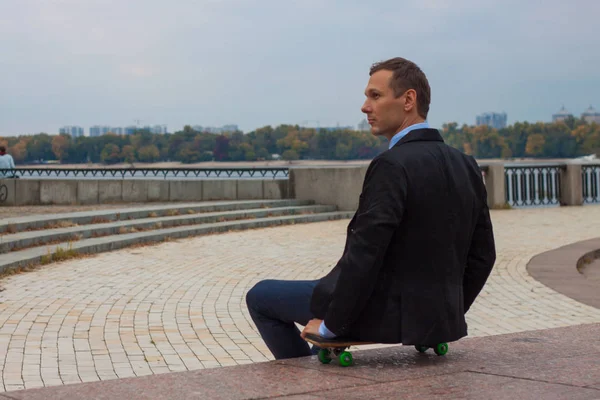 businessman in business suit in the city with skateboard