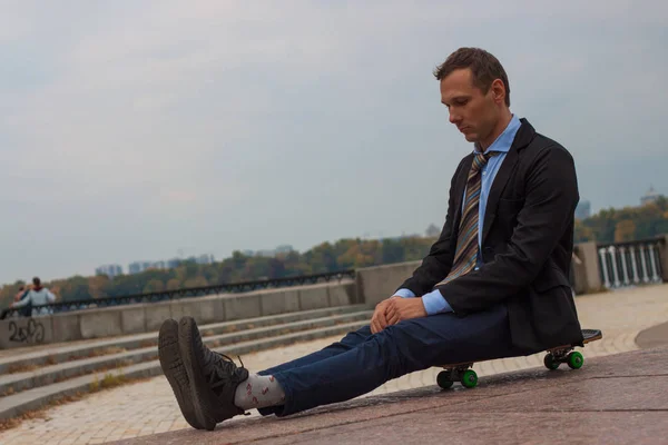 businessman in business suit in the city with skateboard