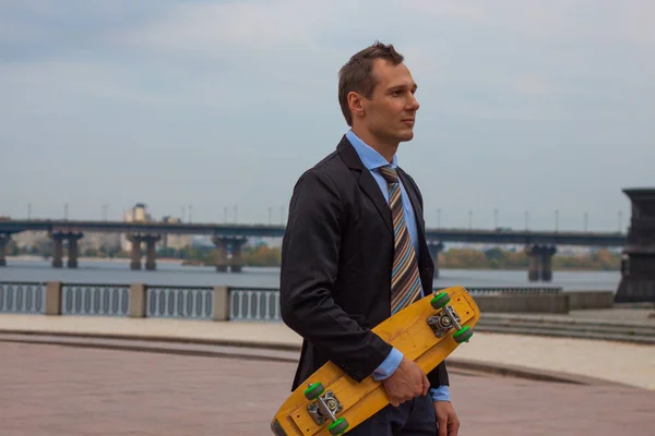 businessman in business suit in the city with skateboard