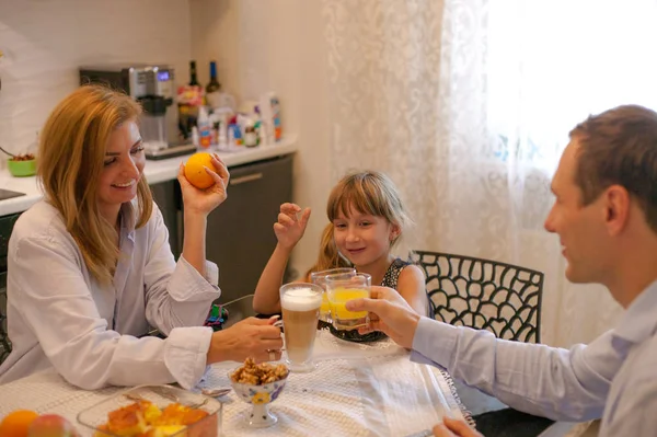 Family have breakfast at the table and drink orange juice in the morning.