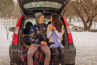 Güzel Uluslararası çift doğa kışın rahatlatıcı. Karda birkaç içinde aşkın romantik toplantı. Genç bir çift gövde ve içecek çay oturmak.