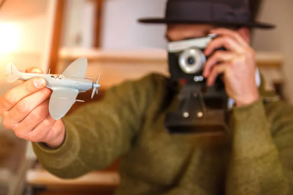 一个戴着帽子的快乐青年拿着一架飞机 地图正在公寓里准备旅行 他的脖子上挂着一台相机 — 图库照片