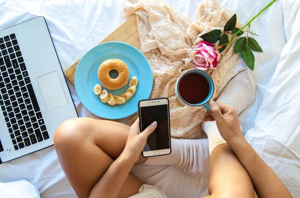 Wanita Minum Kopi Rumah Tempat Tidurnya Sambil Memeriksa Laptopnya — Stok Foto