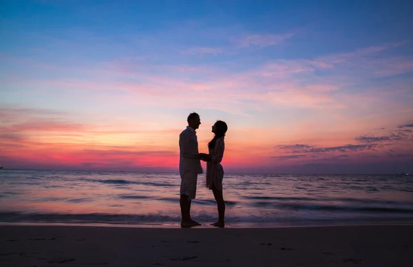 Silhouette of a loving couple holding hands at sunset on the sea.