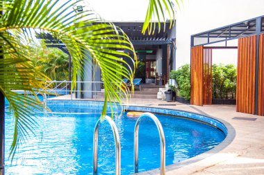 Palmiye ağaçları ile otelin yüzme havuzlu güzel manzara.