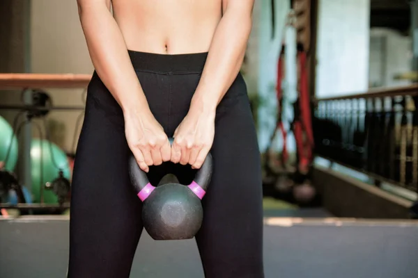 Fit  girl in sports lifts weight doing core exercises in the gym.