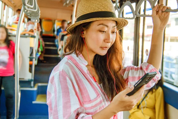 Asian girl with earphone standing on the bus enjoying the trip. | Stock  Images Page | Everypixel