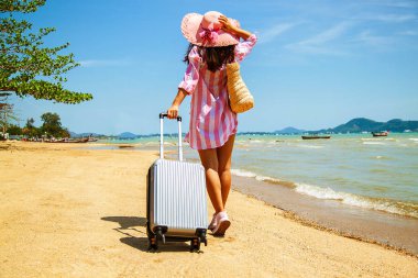 Bavul muhteşem deniz arka planda, seyahat için zaman kavramı ile bir şapka ayakta olan güzel kadın.