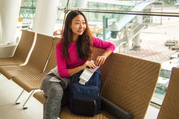 Havaalanında pencerenin yakınında onu uçuş bekleyen genç güzel Asyalı kadın turist.