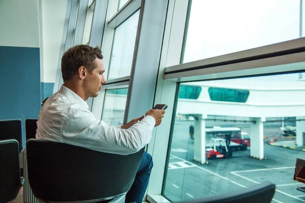 Επιχειρηματικός Άνθρωπος Κοιτάει Τηλέφωνό Του Και Περιμένει Την Πτήση Του — Φωτογραφία Αρχείου