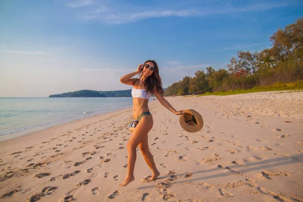 A beautiful asian young woman in bikini dancing with smile  on a sandy beach in Thailand.
