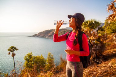 Yalnız kadın backpacker su bir içki için durur ve bir dağın tepesinden görünümü sahiptir .