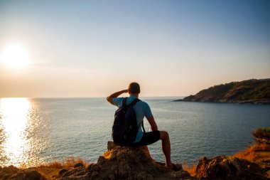 Bir turist veya gezgin bir sırt çantası ile bir tepe üstünde duran ve okyanus veya deniz güzel manzarasına hayran. Yürüme veya yürüyüş.