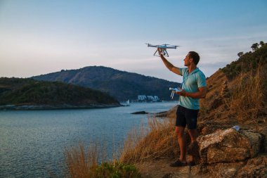 Gün batımında denizin üzerinde uçan insansız hava aracı. İnsan ıslığı havadan indiriyor. Gün batımı fotoğraf havadan.