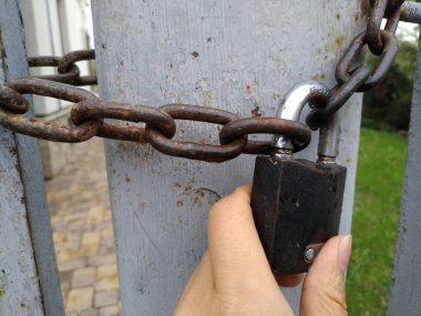 Ferforje bir kapıyı çevreleyen paslı bir zinciri kapatan eski kilit.