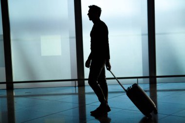Havaalanı dışında çantayla yürüyen işadamının arka görünümü. Genç iş seyahati bavul çekerek.