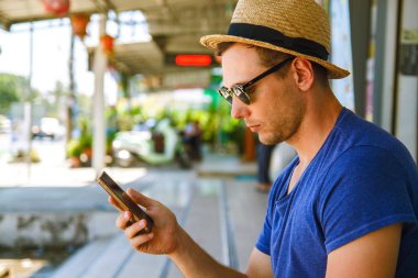 Genç yakışıklı adam gülümseyerek cep telefonuna bakıyor..