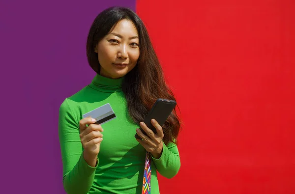 Feliz Asiático Mujer Celebración Tarjeta Crédito Teléfono Inteligente Colorido Fondo — Foto de Stock