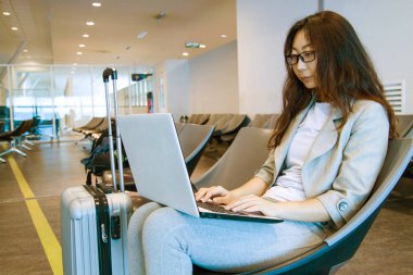 Bir dizüstü bilgisayar klavye kapalı havaalanında yazarak tur tutan genç kadın.