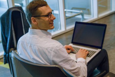 elinde dizüstü bilgisayar ve akıllı telefon ile havaalanı salonunda çalışan yakışıklı orta yaş adam. iş kavramı.