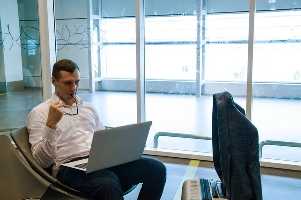 Havaalanında wi-fi internet kullanarak bir dizüstü bilgisayar üzerinde çalışan beyaz iş adamı. 