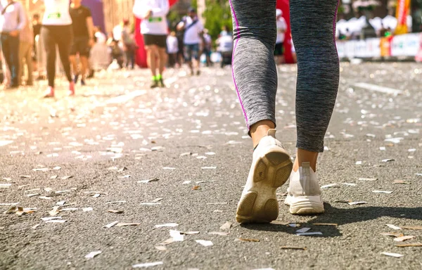 Girl legs in white sport shoes standing on a running track with stadium stands. Sports and healthy concept.