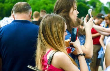 İnsanlar berrak gökyüzüne karşı mobil yükseltiyor. İnternet ve mobil cihaza bağımlılık.