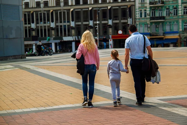 Back view of happy family walking the street of old city holding hands.