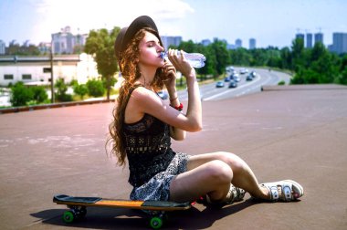 kız bir kaykay üzerinde oturuyor ve içme suyu bir yaz günü olduğunu.