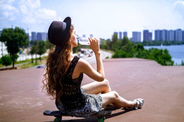 kız bir kaykay üzerinde oturuyor ve içme suyu bir yaz günü olduğunu.