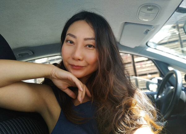 Portrait of a beautiful asian woman sitting in a car and smiling.